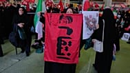 يرفع أحد المعزين رايةً تحمل صورةً للمرشد الأعلى الراحل آية الله علي خامنئي وكلمةً بالفارسية تعني "الانتقام"،