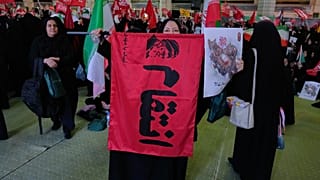 يرفع أحد المعزين رايةً تحمل صورةً للمرشد الأعلى الراحل آية الله علي خامنئي وكلمةً بالفارسية تعني "الانتقام"،