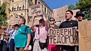 People hold banners and chant "Shame, shame" during a protest against the defence minister's dismissal