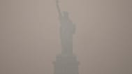 The Statue of Liberty stands during sunset as smoke from wildfires blankets the sky, Thursday, July 16, 2026, in the Brooklyn borough of New York. 
