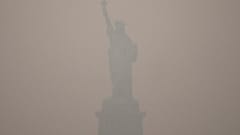 The Statue of Liberty stands during sunset as smoke from wildfires blankets the sky, Thursday, July 16, 2026, in the Brooklyn borough of New York. 