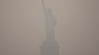 The Statue of Liberty stands during sunset as smoke from wildfires blankets the sky, Thursday, July 16, 2026, in the Brooklyn borough of New York. 