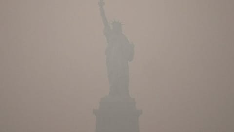 The Statue of Liberty stands during sunset as smoke from wildfires blankets the sky, Thursday, July 16, 2026, in the Brooklyn borough of New York. 