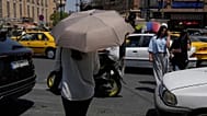 امرأة تختبئ من الشمس تحت مظلة أثناء عبورها تقاطعًا حول السوق الرئيسي التقليدي في طهران، إيران، الخميس 16 يوليو 2026. (AP Photo/فاهد سليمي)