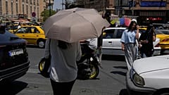 امرأة تختبئ من الشمس تحت مظلة أثناء عبورها تقاطعًا حول السوق الرئيسي التقليدي في طهران، إيران، الخميس 16 يوليو 2026. (AP Photo/فاهد سليمي)