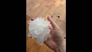 A resident holds a giant hailstone after violent storms swept through France.