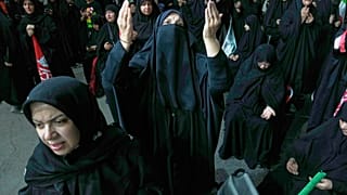 Una donna prega durante una manifestazione a sostegno del governo in una piazza di Teheran, venerdì 17 luglio 2026