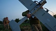 جندي أوكراني من لواء K-2 التابع لقوات الأنظمة غير المأهولة يحمل طائرة بدون طيار متوسطة المدى في موقع الإقلاع قبل أن يطير نحو المواقع الروسية على خط المواجهة في منطقة دونيتسك