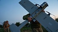 A Ukrainian serviceman of K-2 brigade of the Unmanned Systems Forces carries a midrange drone on takeoff position before flying towards Russian positions at the frontline.