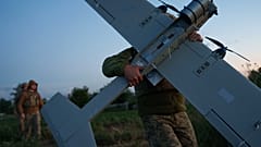 جندي أوكراني من لواء K-2 التابع لقوات الأنظمة غير المأهولة يحمل طائرة بدون طيار متوسطة المدى في موقع الإقلاع قبل أن يطير نحو المواقع الروسية على خط المواجهة في منطقة دونيتسك