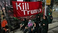 Women sit beneath a banner reading in English, "Kill Trump," during a pro-government rally in Tehran