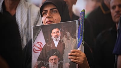 يحمل أحد المعزين صورة تصور المرشد الأعلى الإيراني آية الله مجتبى خامنئي، في الأعلى، ووالده الراحل آية الله علي خامنئي، خلال موكب جنازة خامنئي الأكبر داخل ضريح الإمام علي 