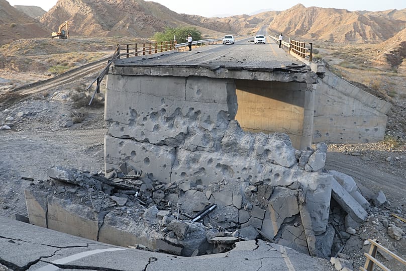 Persone si trovano su un ponte distrutto dopo un attacco nella provincia di Hormozgan, nel sud dell'Iran, sabato 18 luglio 2026.