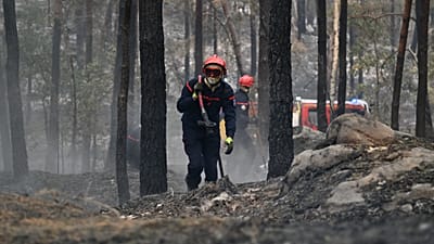Un pompier transporte une lance à incendie après un feu de forêt dans la région de la forêt de Fontainebleau, au sud de Paris, en France, mardi 14 juillet 2026