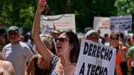 Una donna regge un cartello durante una protesta a Madrid, Spagna, domenica 24 maggio 2026, contro l'aumento dei prezzi delle case.