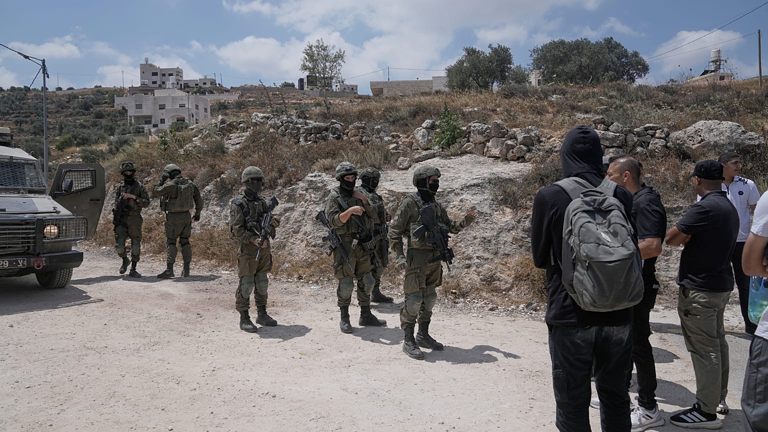 جنود الجيش الإسرائيلي يغلقون الطريق ويمنعون القرويين الفلسطينيين، المدعومين من نشطاء سلام أجانب وإسرائيليين، من الوصول إلى أراضيهم حيث أقام المستوطنون الإسرائيليون بؤرة استيطا