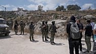 جنود الجيش الإسرائيلي يغلقون الطريق ويمنعون القرويين الفلسطينيين، المدعومين من نشطاء سلام أجانب وإسرائيليين، من الوصول إلى أراضيهم حيث أقام المستوطنون الإسرائيليون بؤرة استيطا