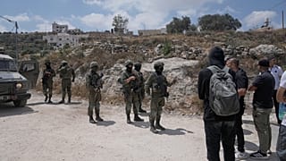 جنود الجيش الإسرائيلي يغلقون الطريق ويمنعون القرويين الفلسطينيين، المدعومين من نشطاء سلام أجانب وإسرائيليين، من الوصول إلى أراضيهم حيث أقام المستوطنون الإسرائيليون بؤرة استيطا
