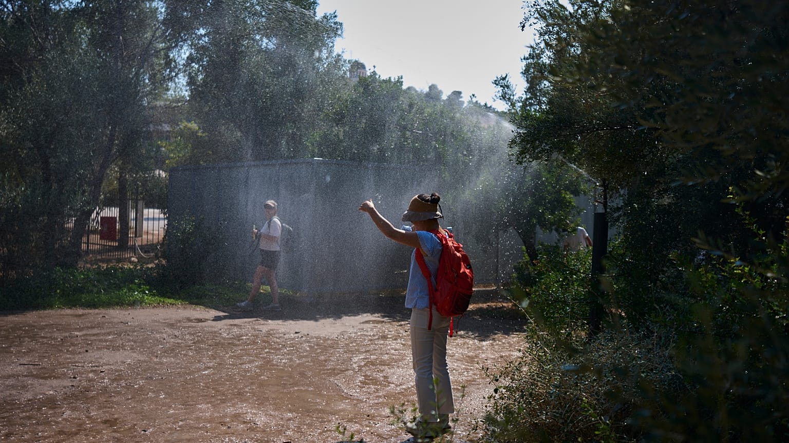 Τουρίστες δροσίζονται στην Αρχαία Αγορά της Αθήνας από το ποτιστικό σύστημα λόγω του ακραίου καύσωνα