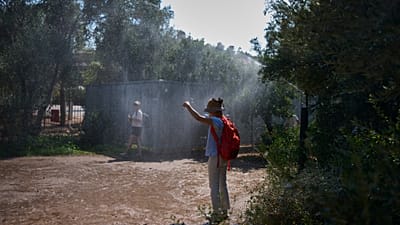 Τουρίστες δροσίζονται στην Αρχαία Αγορά της Αθήνας από το ποτιστικό σύστημα λόγω του ακραίου καύσωνα