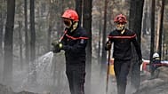 Des pompiers interviennent parmi les arbres calcinés à la suite d'un incendie de forêt dans la région de la forêt de Fontainebleau, au sud de Paris, le 14 juillet 2026