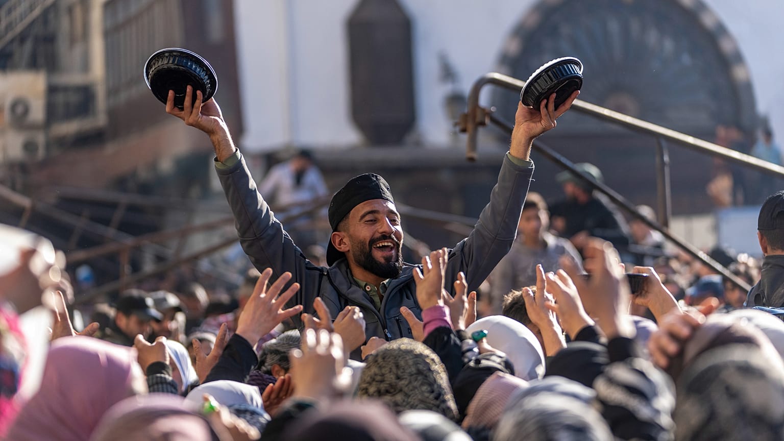 A man distributes rice to people gathering outside the Umayyad Mosque during Friday prayers in Damascus, Sirya, Friday Jan. 10, 2025