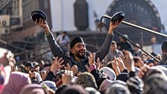 A man distributes rice to people gathering outside the Umayyad Mosque during Friday prayers in Damascus, Sirya, Friday Jan. 10, 2025