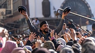 A man distributes rice to people gathering outside the Umayyad Mosque during Friday prayers in Damascus, Sirya, Friday Jan. 10, 2025