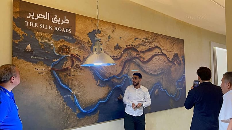 زائرون يقفون أمام لوجة جدارية توضح مسير طريق الحرير في معرض ناس تكس 2026 بمدينة المعارض بدمشق 
