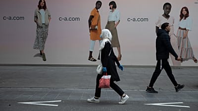 11 Mayıs 2020 Pazartesi tarihli arşiv fotoğrafında, Belçika'nın Anvers kentindeki ana alışveriş caddesinde bir kadın ve bir erkek birbirinin yanından geçiyor.