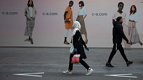 In this Monday, May 11, 2020 file photo, a woman and man walk past each other on a main shopping street in Antwerp, Belgium.