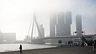 A pedestrian passes Erasmus bridge on a misty morning in the center of Rotterdam, Netherlands, Friday, Sept. 12, 2014.