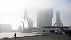 A pedestrian passes Erasmus bridge on a misty morning in the center of Rotterdam, Netherlands, Friday, Sept. 12, 2014.