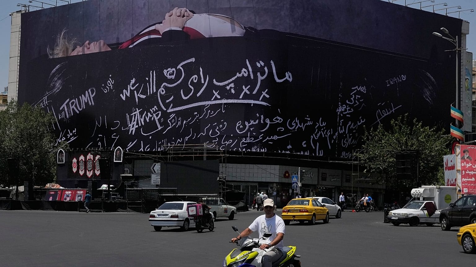 مرت مركبات بجوار لوحة إعلانية في ساحة الثورة الإسلامية وسط طهران تُظهر الرئيس الأميركي دونالد ترامب مستلقياً على ما يبدو أنه نعش وتحمل عبارة "سنقتل ترامب".