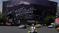 مرت مركبات بجوار لوحة إعلانية في ساحة الثورة الإسلامية وسط طهران تُظهر الرئيس الأميركي دونالد ترامب مستلقياً على ما يبدو أنه نعش وتحمل عبارة "سنقتل ترامب".