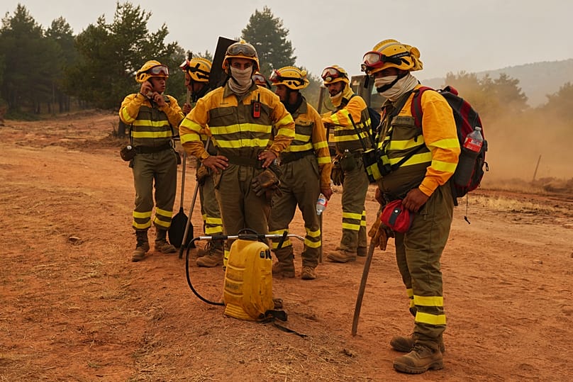 Forest rangers take a break before returning to work on the fire near Condemios de Arriba, Guadalajara province, Spain, Wednesday, July 22, 2026.