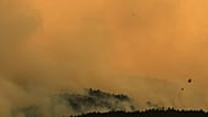 A firefighting helicopter drops water on the flames as a wildfire advances near Condemios de Arriba, Guadalajara province, Spain, Wednesday, July 22, 2026.
