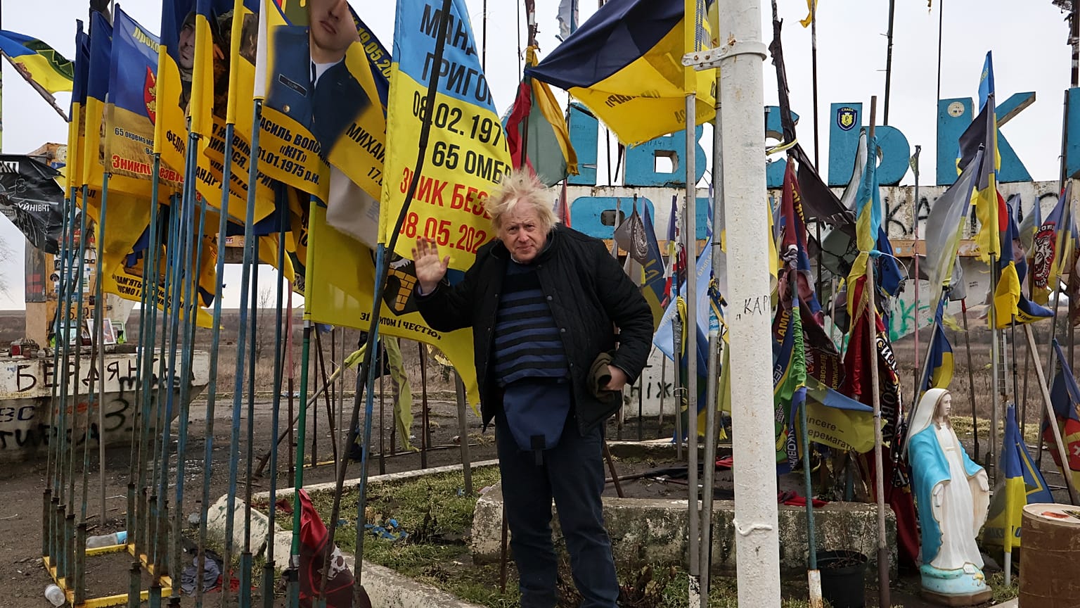 Former British PM Boris Johnson at the city entrance sign surrounded by Ukrainian national flags and flags of military units, Orikhiv in the Zaporizhzhia, 26 February 2026.