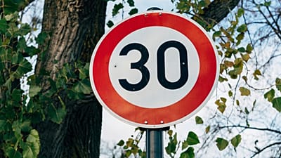 Una señal de límite de velocidad roja y blanca que indica 30 mph.