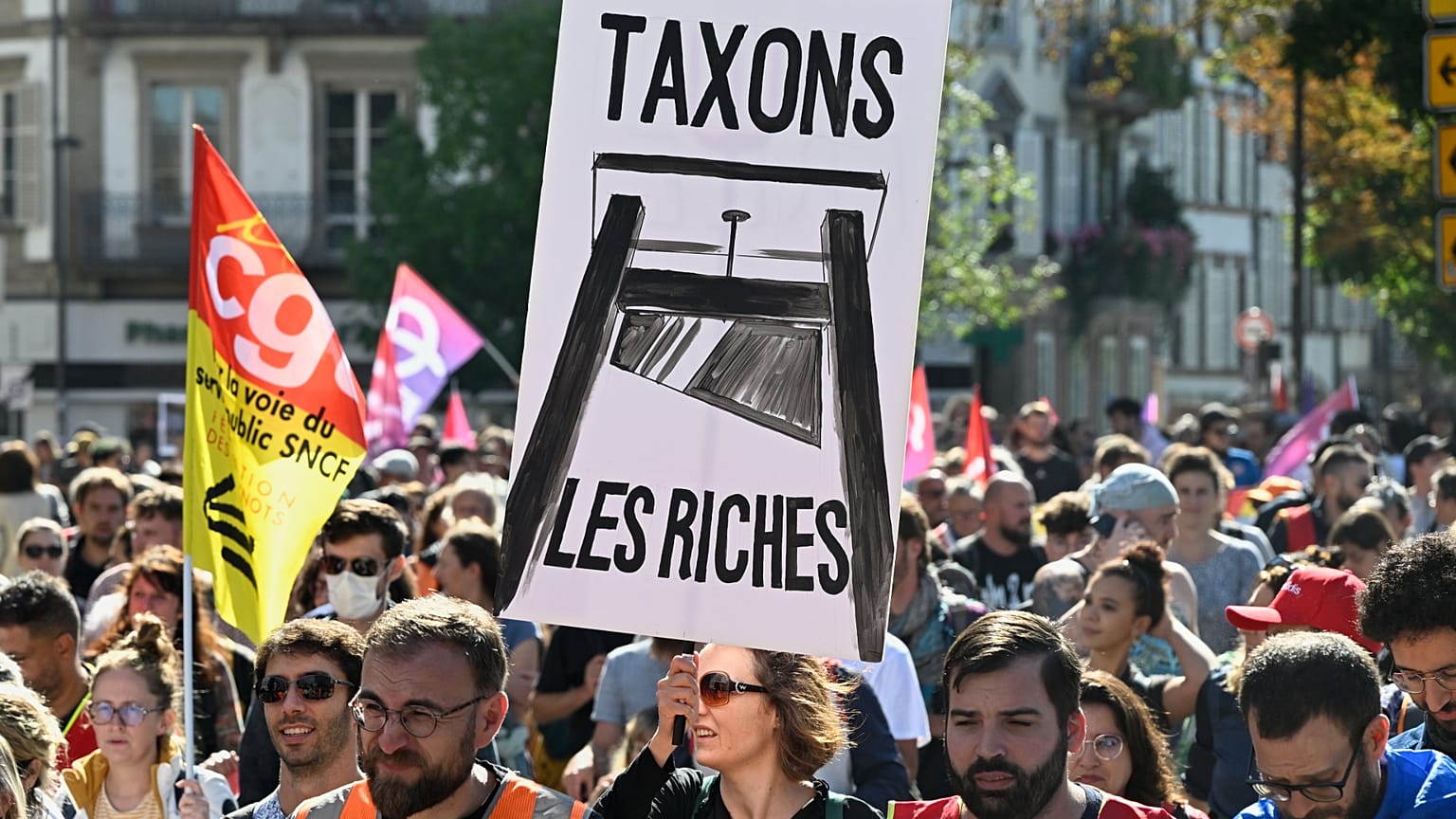 متظاهر يحمل لافتة كتب عليها "let's tax the rich" خلال تجمع لحركة "Block Everything" في ستراسبورغ بشرق فرنسا، الأربعاء العاشر من أيلول 2025. (أ ف ب)