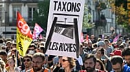 متظاهر يحمل لافتة كتب عليها "let's tax the rich" خلال تجمع لحركة "Block Everything" في ستراسبورغ بشرق فرنسا، الأربعاء العاشر من أيلول 2025. (أ ف ب)