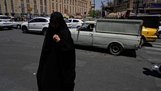 امرأة تمشي بينما تسير المركبات عند تقاطع حول السوق الرئيسي التقليدي في طهران، إيران، الخميس 16 يوليو 2026. (AP Photo/فاهد سليمي)