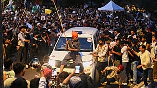 A protestor sits on the hood of a police car during a demonstration demanding educational reforms as part of the Cockroach Janta Party's ongoing protest movement in New Delhi,