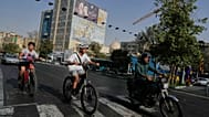 A man rides on his motorbike as boys ride on their bicycles in downtown Tehran, Iran, Wednesday, July 22, 2026. (AP Photo/Vahid Salemi)