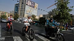 A man rides on his motorbike as boys ride on their bicycles in downtown Tehran, Iran, Wednesday, July 22, 2026. (AP Photo/Vahid Salemi)