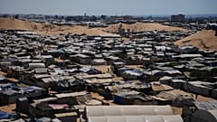 IMAGEM DE ARQUIVO: Palestinianos deslocados caminham entre tendas onde se abrigam num campo improvisado em Khan Younis, sul da Faixa de Gaza, 1 de julho de 2026
