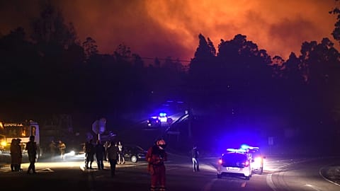 FILE - Police cars block the area as emergency vehicles responded to a wild fire in As Neves, Pontevedra, in the northwestern Spanish region of Galicia, Spain. Oct. 16, 2017. 