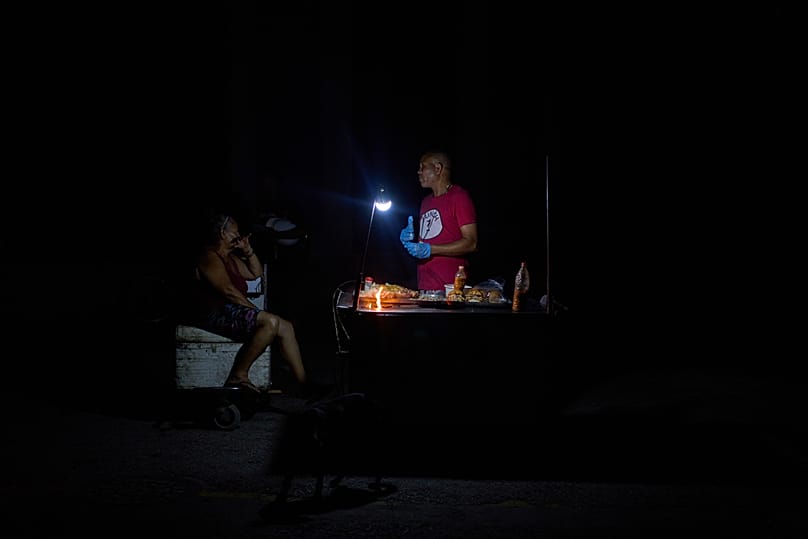 A street vendor stands by his stall selling roast pork sandwiches during a blackout in Havana, Cuba, Tuesday, July 14, 2026. 