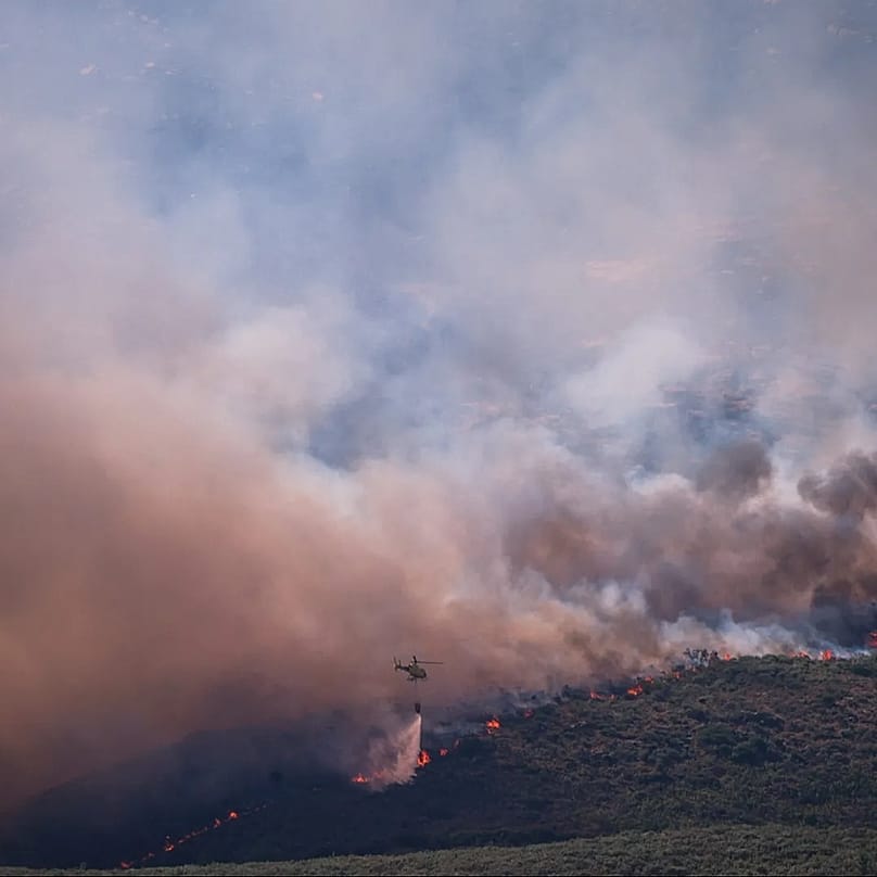 Un helicóptero de extinción de incendios arroja agua sobre las llamas mientras un incendio forestal avanza cerca de Burgohondo, Ávila, España, el 24 de julio de 2026. 