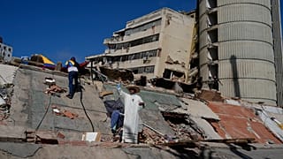 قس كاثوليكي يقف بين أنقاض المباني السكنية المنهارة خلال الزلازل التي ضربت لاجويرا، فنزويلا، الجمعة، 17 يوليو، 2026. (AP Photo/Ariana Cubillos)